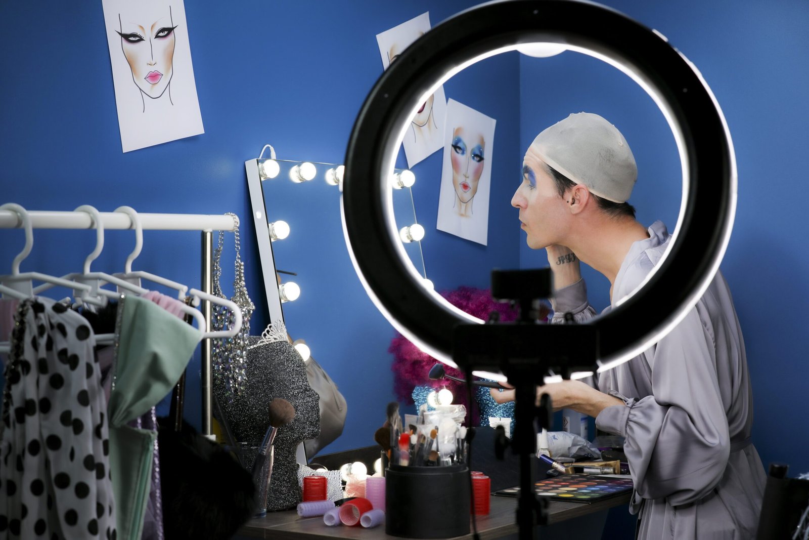 Makeup artist applying dramatic look under ring light in professional studio setup for beauty product photography