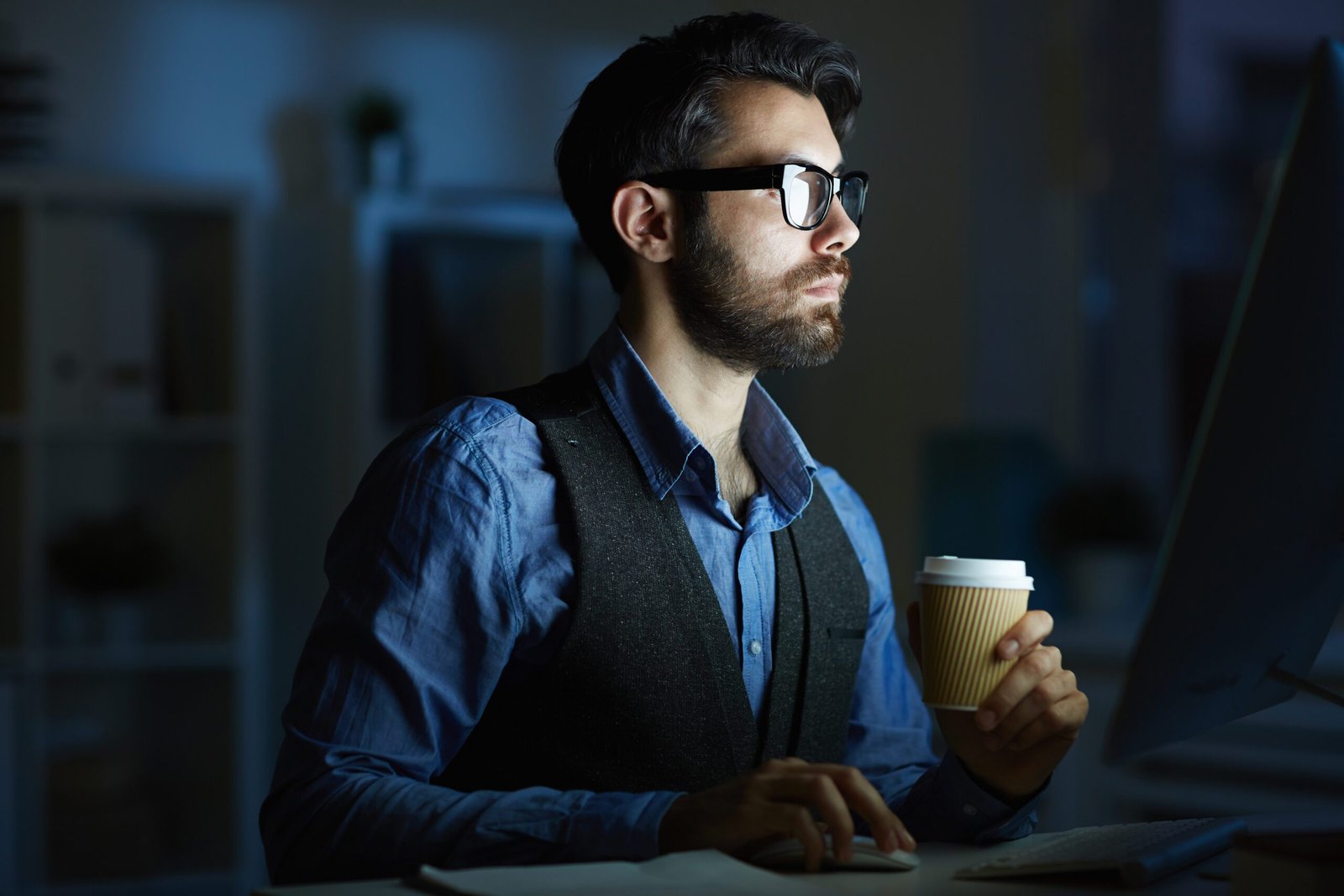 Digital Tide executive team member working late at computer with coffee in modern office
