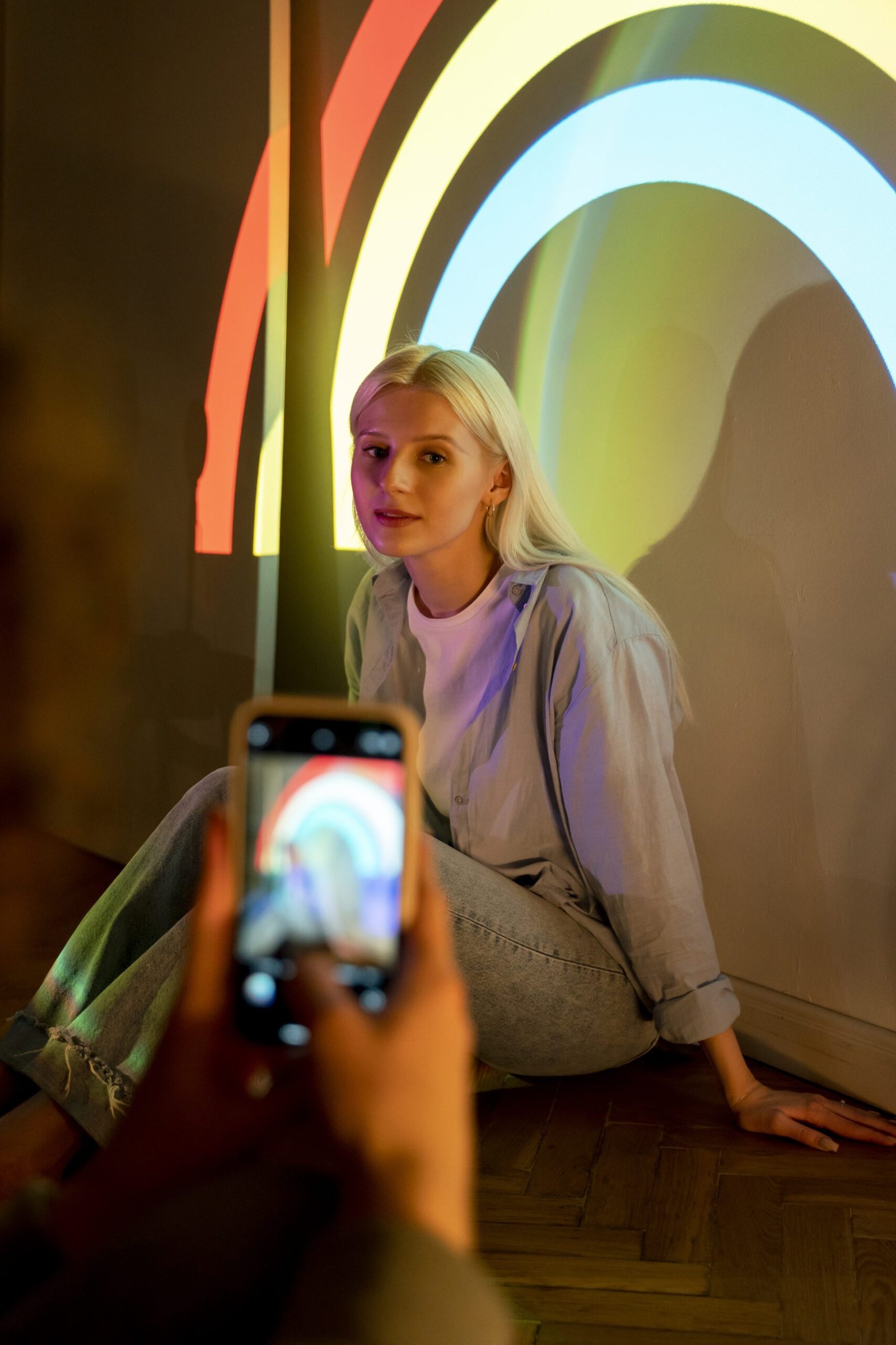 Young content creator posing with rainbow light while being photographed for Instagram marketing