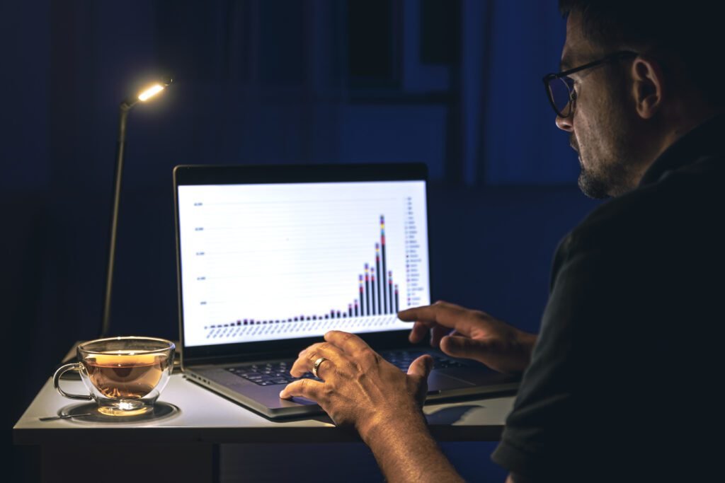 Digital marketer analyzing LinkedIn advertising campaign performance on laptop at night